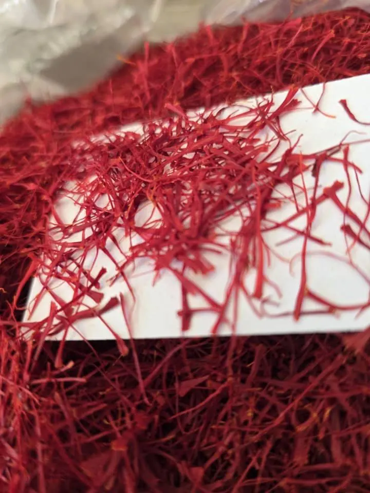 Saffron threads laid across a white card above a full bag