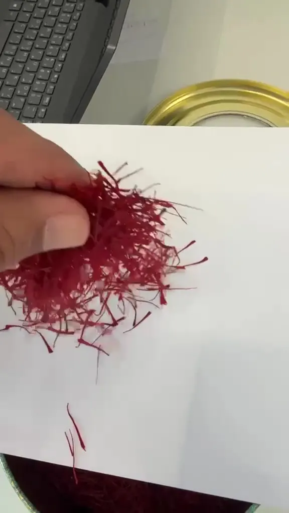 Saffron threads released onto white paper to show length and colour